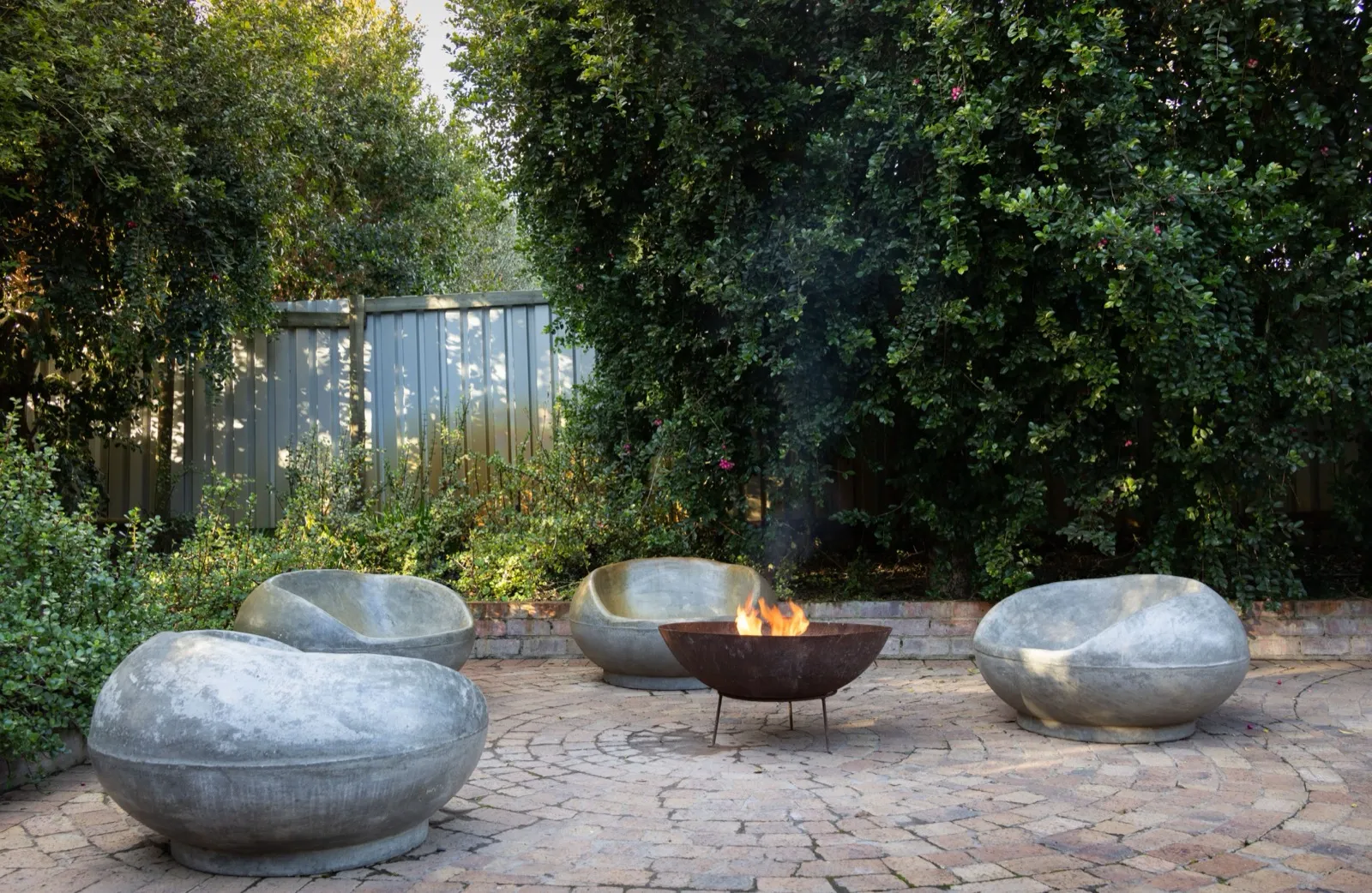 Stone outdoor fireplace with seating area for a luxury West County backyard
